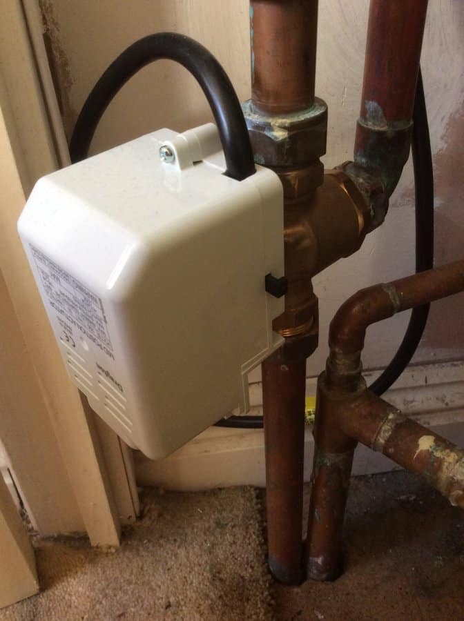 Close-up of a white Grundfos circulating pump mounted on copper pipework in a utility cupboard