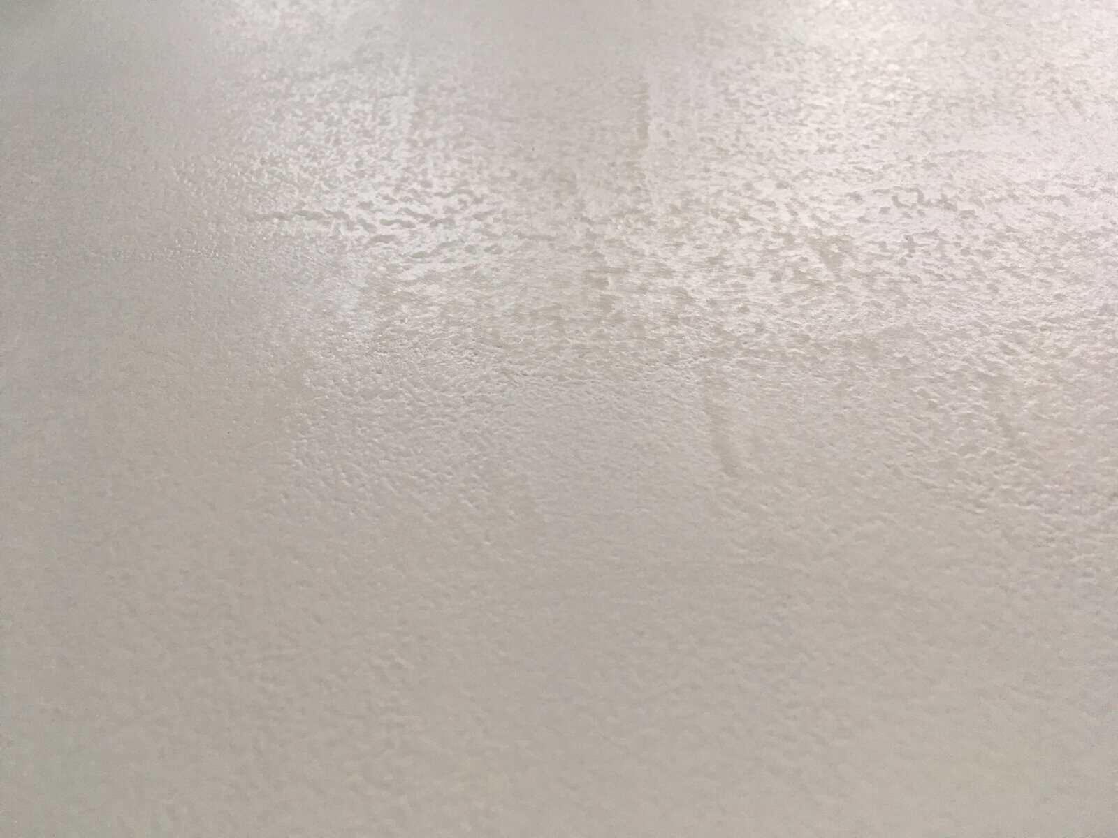 Close-up of a white painted MDF surface showing an uneven, rippled texture caused by shellac primer drying too quickly in hot conditions.