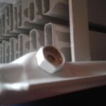 Close-up of a radiator bleed valve with the square-drive spindle sheared off, leaving only the hexagonal brass body visible at the end of the radiator header.