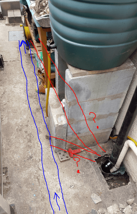 Wide view of a Victorian side return with annotated blue lines showing rainwater run-off paths across the yard, red lines indicating the underground drain route, and red question marks at two uncertain junctions near the gully and inspection chamber.