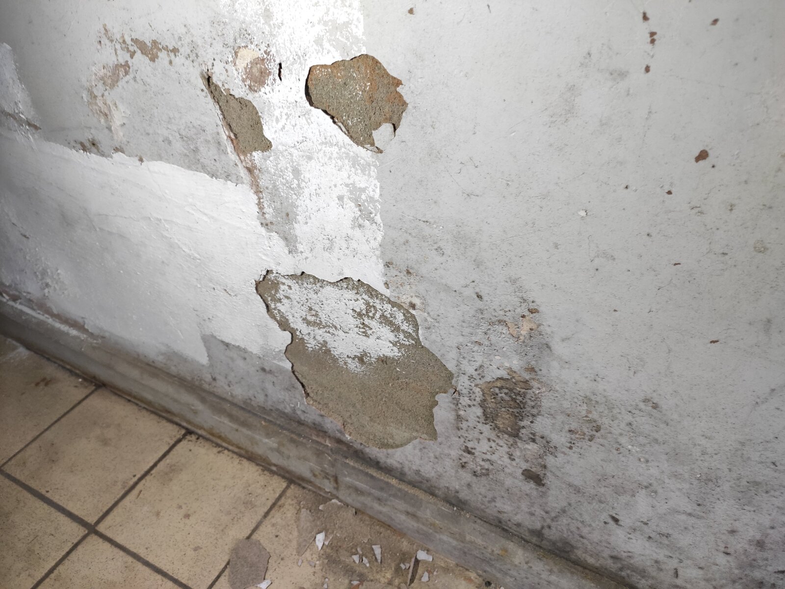 Odd bubbles flaking paint on the wall, white powder behind paint