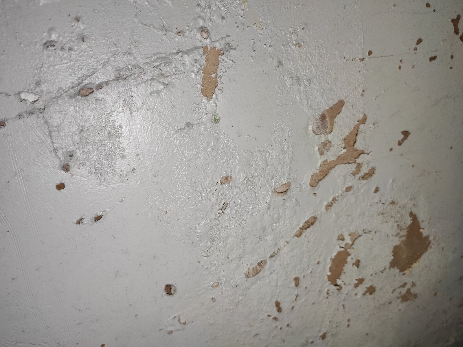 Odd bubbles flaking paint on the wall, white powder behind paint