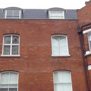 Damp patches on wall beneath gulley